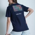 Woman in denim shorts and graphic t-shirt posing against a white background.