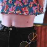Close-up of a floral crop top paired with high-waist jeans and sunglasses.
