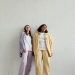 Two women pose indoors in stylish pastel pajamas, exuding relaxed and fashionable vibes.