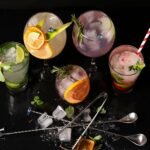 A vibrant assortment of cocktails garnished with citrus slices and mint leaves, perfect for a summer gathering.