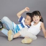 Two children playing joyfully on a studio backdrop, showcasing happiness and togetherness.