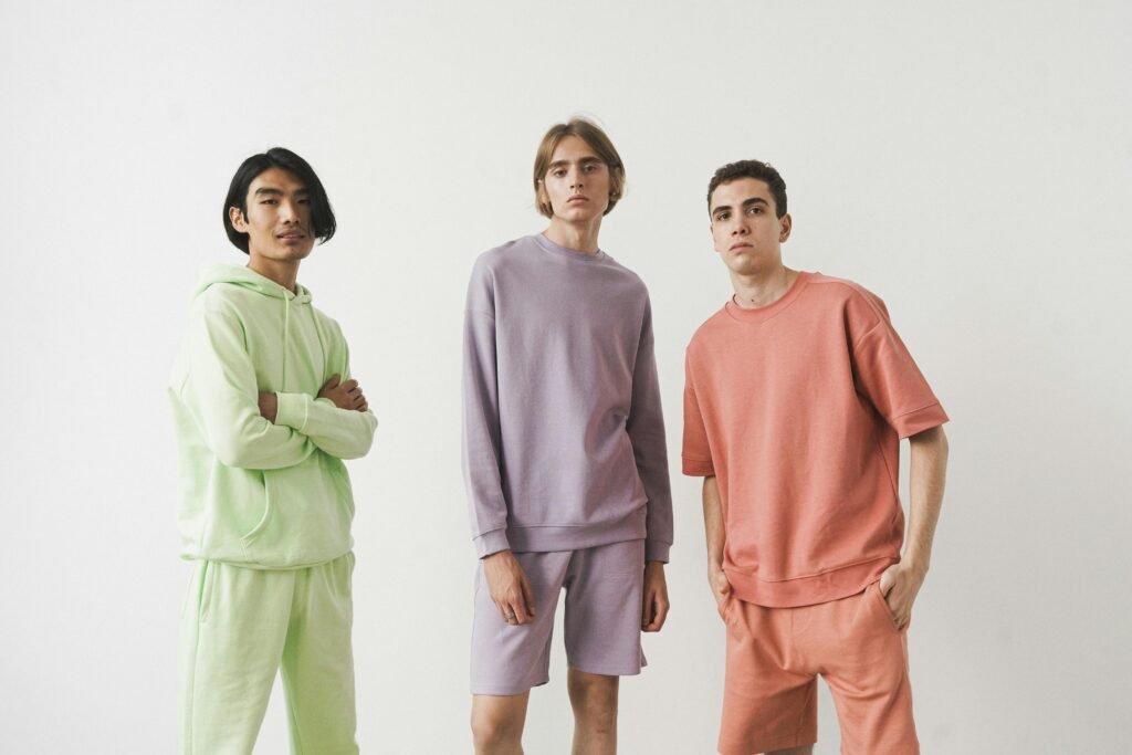 Three men wearing pastel loungewear poses in a studio, showcasing modern casual fashion.